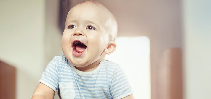 baby smiling happily at someone out of frame