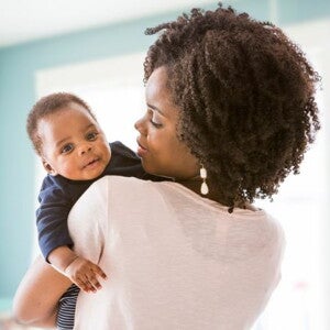 Mother in white tshirt holding her baby who is looking over her shoulder
