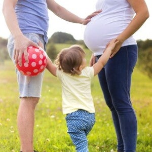 Pregnant woman with man and toddler in a field