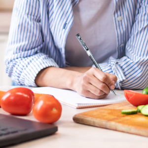 writing down a menu in the kitchen with food around