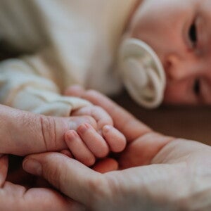 Parents holding their new babies hand while they lie down