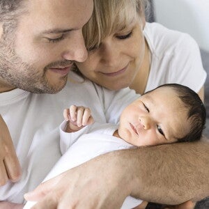 parents in white shirts holding their young baby