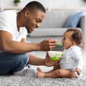 man feeding his child with a spoon