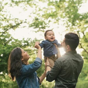mother and father holding toddler in the air