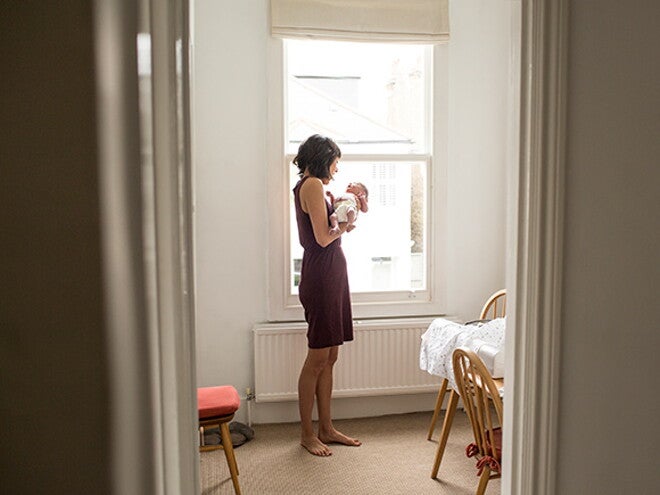 Woman in a black dress holding her baby in a room